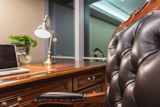 笔记本电脑和灯在豪华的办公室内部木桌与皮革扶手椅图片下载