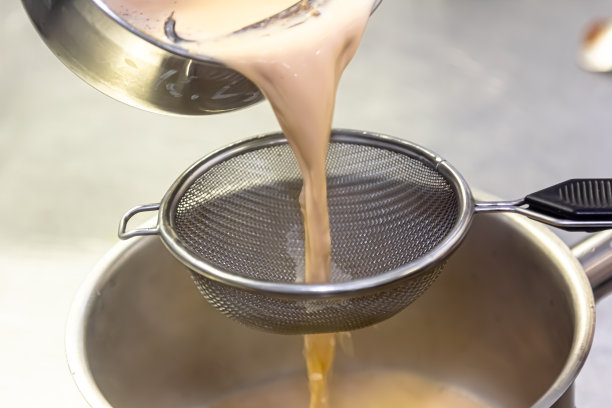 在餐厅厨房做饭。用筛子筛酱汁。厨师正在过滤酱汁。高质量照片图片下载