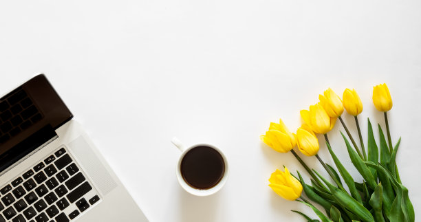 笔记本电脑，一杯咖啡和一束白色背景的郁金香，俯视图。图片下载