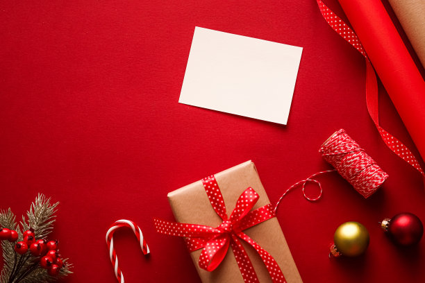 圣诞饰品，礼品和装饰与白色空白的问候或名片或感谢便条在喜庆的红色背景作为节日快乐的平面图片下载
