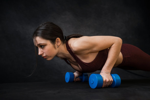 漂亮苗条的女人穿着运动服，用黑色的哑铃做练习图片下载