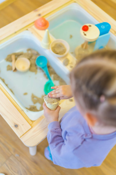 小女孩在玩动沙和木制玩具。感官发展与体验，儿童主题活动，精细运动技能发展图片下载