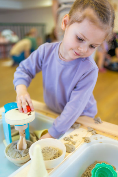 小女孩在玩动沙和木制玩具。感官发展与体验，儿童主题活动，精细运动技能发展图片下载