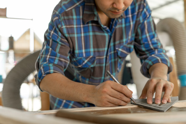 木匠正在用尺子和铅笔检查和标记要切割的点。业主一个小木材业务是加工家具生产。图片下载