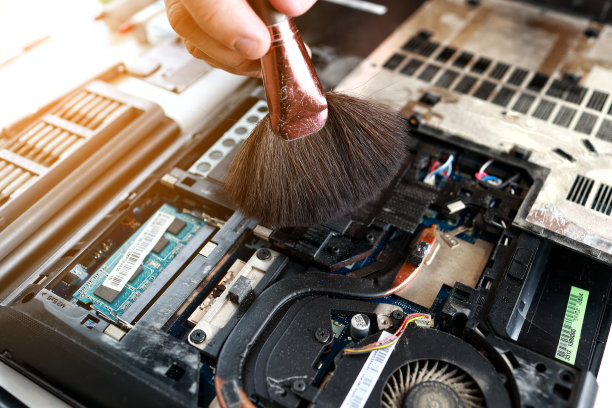 修理工正在用刷子清洗拆卸下来的笔记本电脑部件。技术支持和解决设备问题。维修、清洁、保养电脑。修理店。硬件维护。图片下载