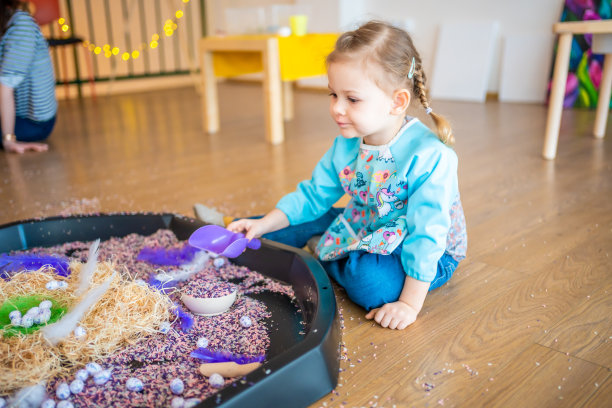 小女孩在玩五彩大米。感官发展与体验，儿童主题活动，精细运动技能发展图片下载