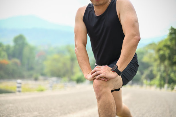 裁剪的图片，一个运动的亚洲男子穿着运动服伸展他的腿图片下载