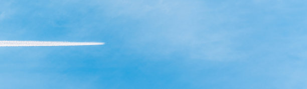一架飞机和一架飞机在蓝色的夏日天空上留下的白色航迹。飞机飞过蓝天，留下长长的水汽尾迹。副本的空间。横幅广告。图片下载
