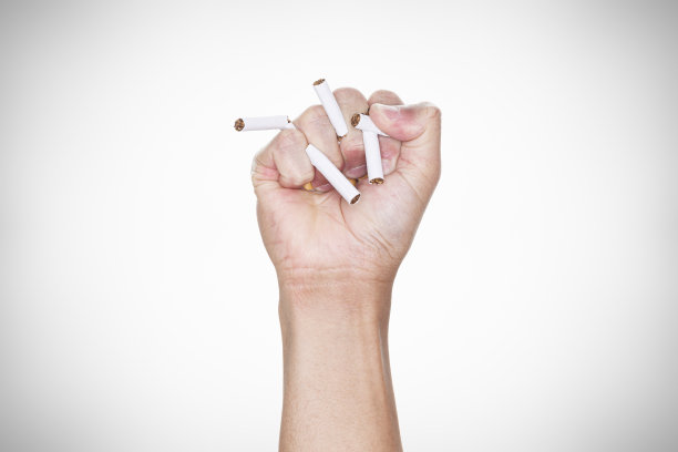 灰色背景上，男性的手捏着香烟。戒烟。世界无烟日概念。图片下载