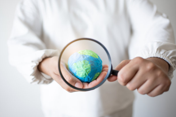 手里拿着土纸和放大镜。保护世界免受全球变暖影响的理念图片下载
