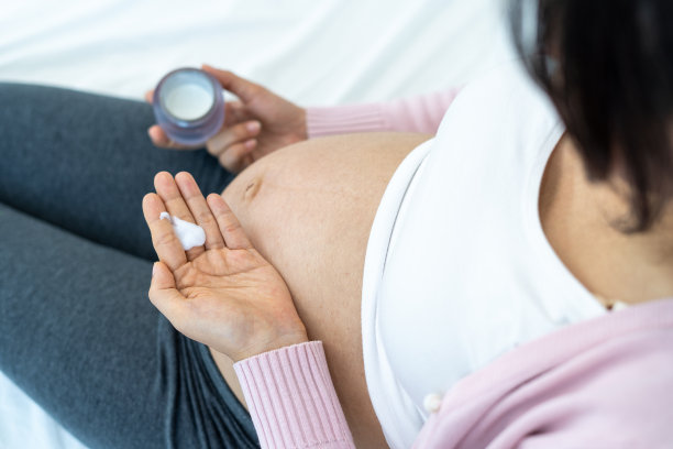 孕妇选择婴儿安全的护肤霜。怀孕29周的孕妇准备在腹部涂一种保湿霜来防止妊娠纹。母亲怀孕期间的皮肤护理图片下载