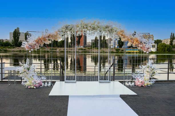 现代美丽的大型婚礼拱门，河岸上有许多鲜花。图片下载