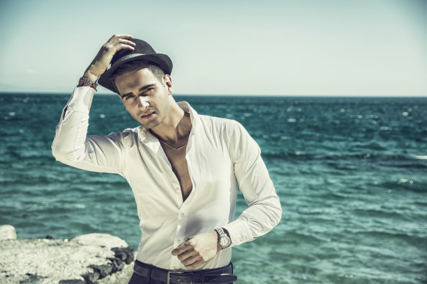 沙滩上穿白衬衫戴白帽子的帅哥图片下载