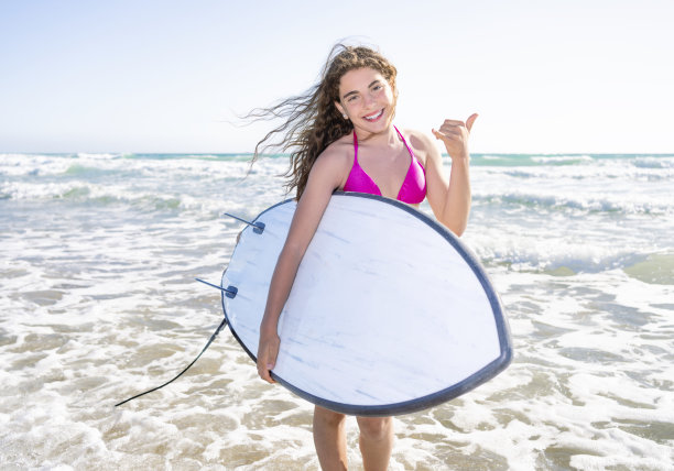 微笑的女人拿着冲浪板在海边让沙卡唱歌图片下载