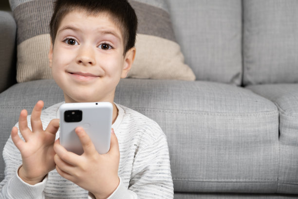 一个学龄前男孩使用智能手机，用手机玩游戏，发短信图片下载