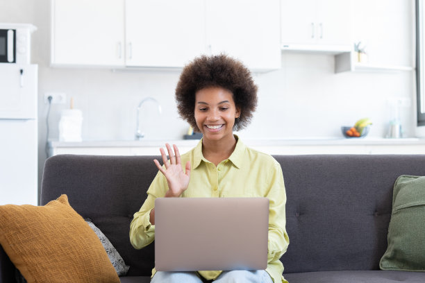 容易学习。微笑的年轻混血女士坐在沙发上，用笔记本电脑搜索信息，观看网络研讨会视频课程。积极的黑人女性利用在线教育服务提高挥动技能图片下载