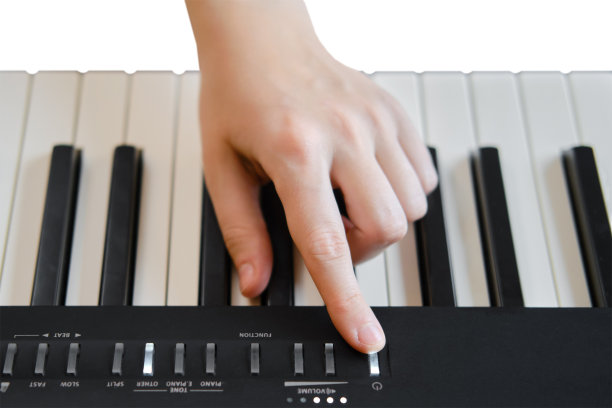 一个成年妇女在弹奏电子琴，双手特写，孤立在白色背景上。女性的手放在便携式电子钢琴的按钮上图片下载