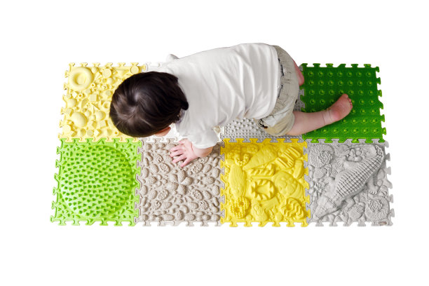 婴儿蹒跚学步的脚在医疗矫形垫上的特写，孤立在白色背景上。孩子的腿和平足放在医疗地毯上，孤立在白色背景上。一岁四个月大的孩子图片下载