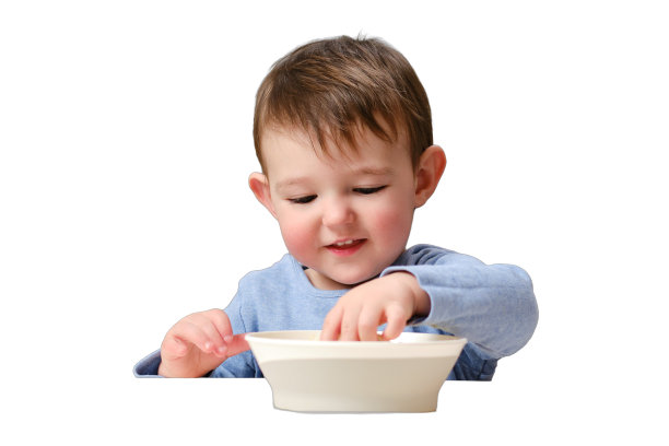 快乐的孩子坐在厨房的椅子上吃着一个磨碎的苹果，孤立在白色的背景上。微笑的男婴一岁四个月大图片下载