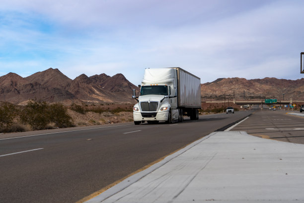 日落时分，一辆白色的半挂车穿过内华达沙漠，它强大的存在与广阔的景观形成鲜明对比。雄伟的山脉构成了这一场景，描绘了一个令人叹为观止的背景。图片下载