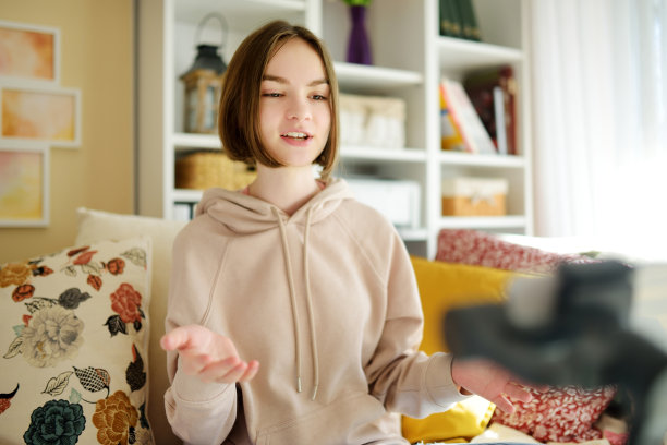 美丽的少女用她的智能手机录制视频博客。年轻的视频博主在家拍摄视频。青少年网红为她的社交媒体账户创建内容。图片下载