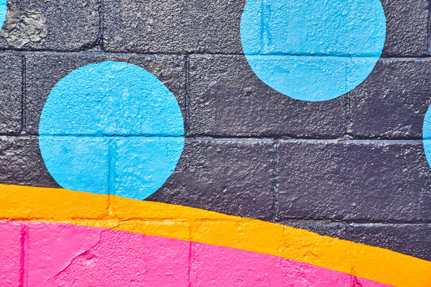 涂有黑色、橙色、粉色和蓝色圆圈的水泥墙图片下载