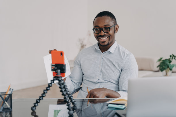 非洲自由职业者在智能手机上进行在线头脑风暴。快乐的人展示了数据文件。图片下载