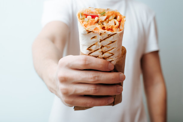 特写的不认识的人展示沙瓦玛，烤肉串或馅饼面包。快餐广告图片下载