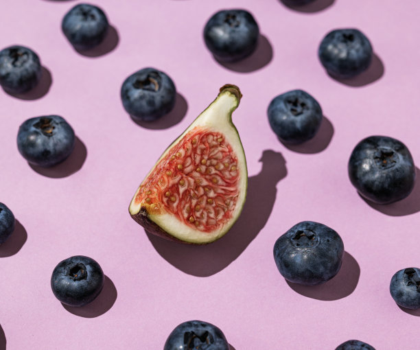 布局新鲜蓝莓和一片无花果在紫色的背景近距离。水果图案壁纸或广告横幅图片下载