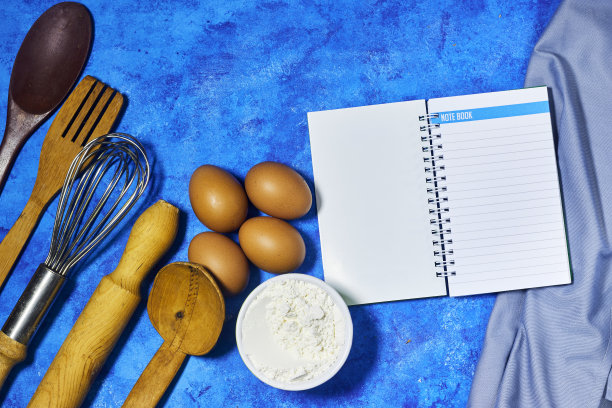 空白的老式食谱烹饪书和器皿与鸡蛋和面粉碗。顶部视图与复制空间在蓝色grunge背景图片下载