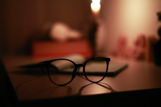 在黑暗的房间里，烛台上燃烧的蜡烛照亮了办公桌上的纸笔记本和笔和眼镜。停电时在家学习和工作。电力问题图片下载