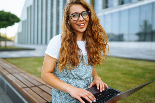 拿着笔记本电脑的年轻女子在户外工作图片下载