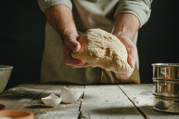 男性手握生面团的特写，黑色背景图片下载