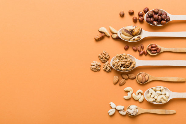 用白色木勺混合坚果。在彩色背景上混合各种坚果。开心果、腰果、核桃、榛子、花生和巴西坚果图片下载