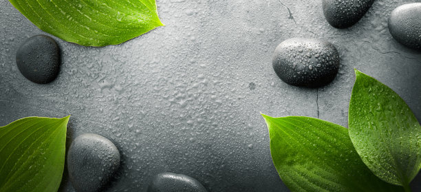 深色温泉背景。黑色的按摩石和潮湿的绿叶。带有复制空间的横幅图片下载