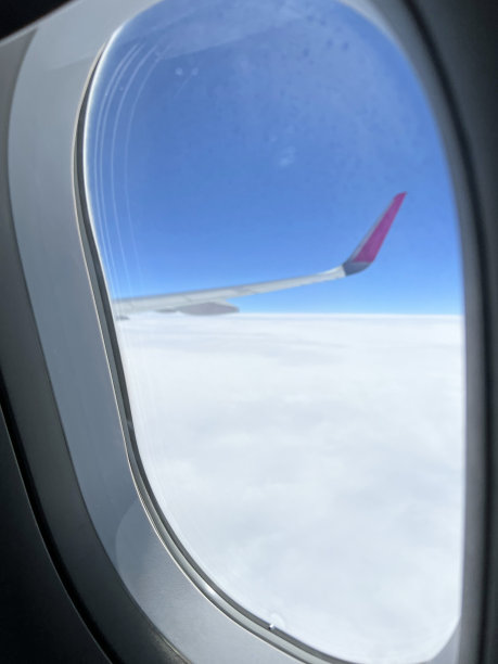 从飞机窗口看到的风景。美丽的云景和蓝天。透过飞机窗户看到的白云之上的美丽全景。乘飞机旅行概念图片下载