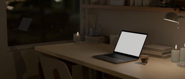 夜晚的家庭工作空间，在黑暗的房间里，笔记本电脑模型放在木桌上。图片下载