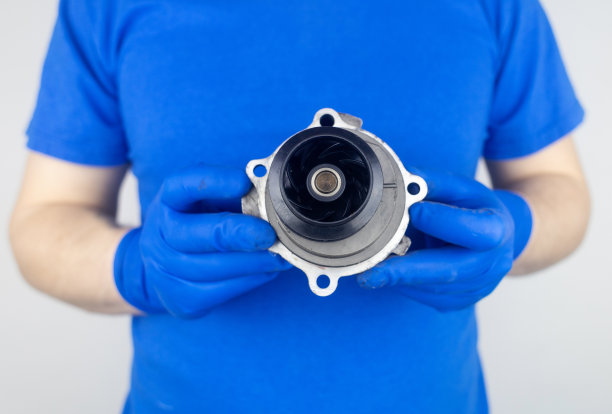 正时皮带破裂。更换故障的发动机传动带。橡胶裂缝和电线断裂的危险。按规定更换设备。戴蓝手套的技工图片下载