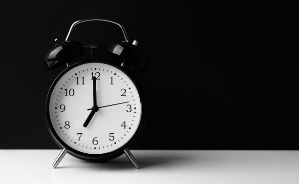 黑色闹钟，白色桌子，黑色背景。图片下载