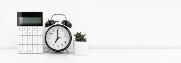 黑色闹钟和计算器靠在白色的墙上。金融的概念。图片下载