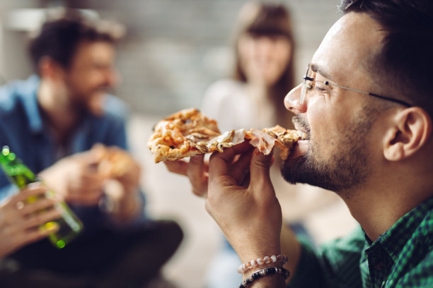 一个快乐的男人和他的朋友们一起吃披萨的特写图片下载