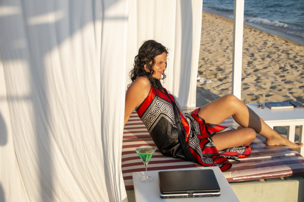 中年女商人躺在沙滩上的躺椅上休息。图片下载