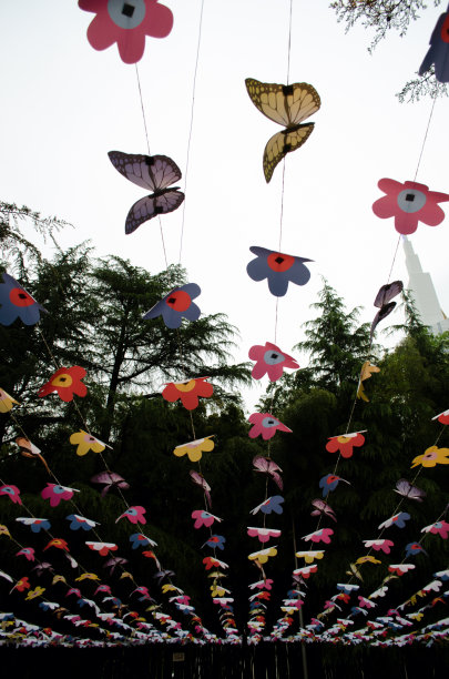 在城市公园的人行道上悬挂着绳子上的装饰品，在鲜花和蝴蝶的视频中装饰，垂直照片为股票图片下载
