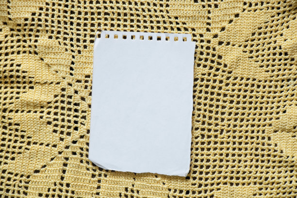 在一张黄色的蕾丝餐巾上放着一张带有记事本的白纸，为文字留出空间图片下载