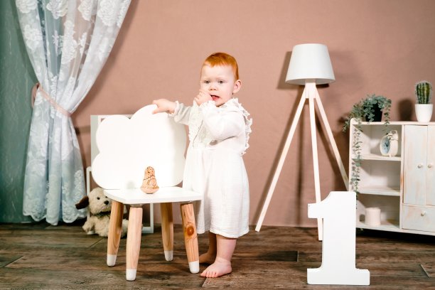 红发小女孩庆祝一周岁生日。1年家庭聚会专业照相馆摄影。可爱可爱的红发孩子穿着白色的复古连衣裙。家里的儿童房图片下载