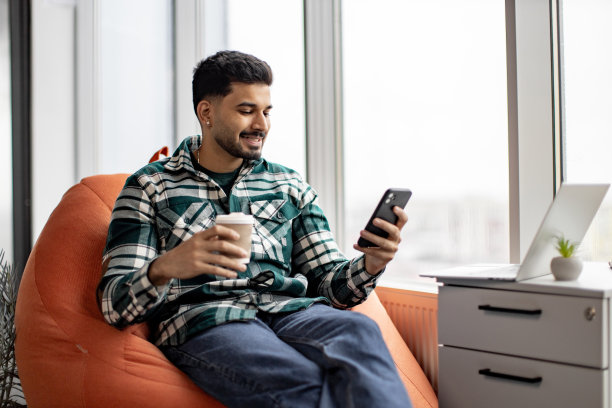 自由职业者在工作场所喝咖啡休息时使用手机图片下载