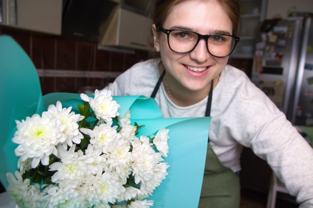 花店的女人微笑着拿着一束白色的雏菊。一个联邦应急管理局图片下载
