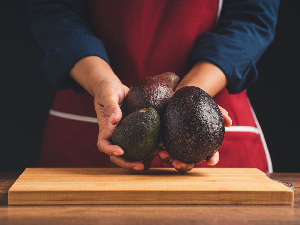 站在厨房里，手拿三个牛油果的特写。图片下载