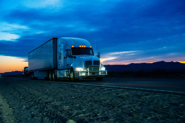 日落时分，一辆白色半挂车穿过内华达沙漠。在雄伟的群山的映衬下，卡车继续行驶，身后留下了一缕灰尘，这一天即将结束。图片下载
