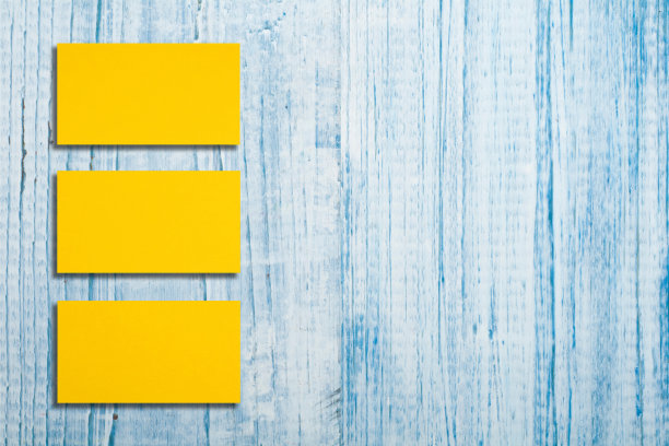 水平黄金名片堆叠的模型排列在蓝色的木制背景。图片下载